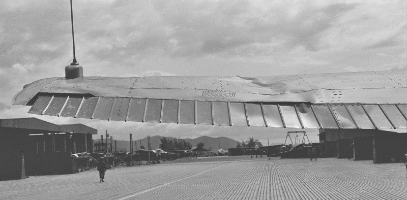 same plane looking west on ramp. The hanger is to the left of the man walking West. Just beyond the 2 or 3 vertical posts in front of the man is the company U-6 Beaver. Not the A-Frame engine hoist straight ahead past the O–1. The building just past the last revetment is the crew chief/small engine change hanger building. And just beyond the last O–1 that is approaching the ram at an angle is the access to the taxiway leading to the runway